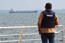 A journalist watches as the bulk carrier Razoni starts its way from the port in Odesa, Ukraine, ...