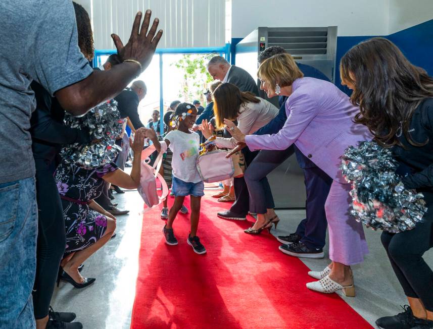 U.S. Rep. Susie Lee, right, gives a high five to a student while joined by many others in a red ...