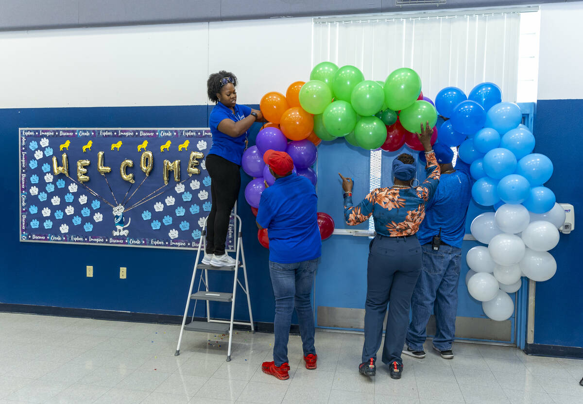 Employees hang balloons over doors where students will pass under during a red carpet welcome f ...