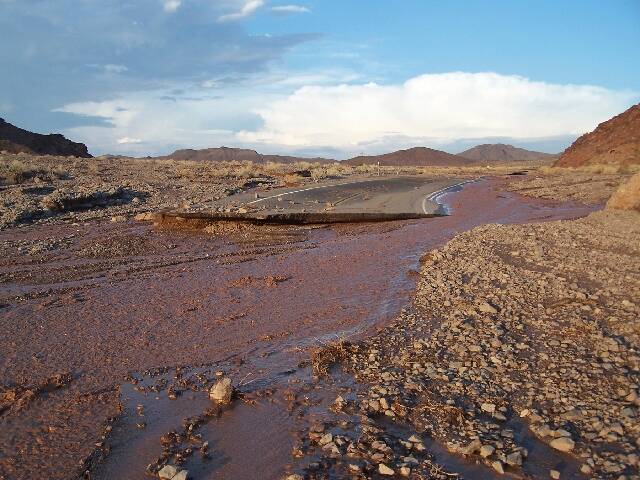 Flood water from a July 28, 2013, storm flows past a washed out section of Badwater Road in Dea ...