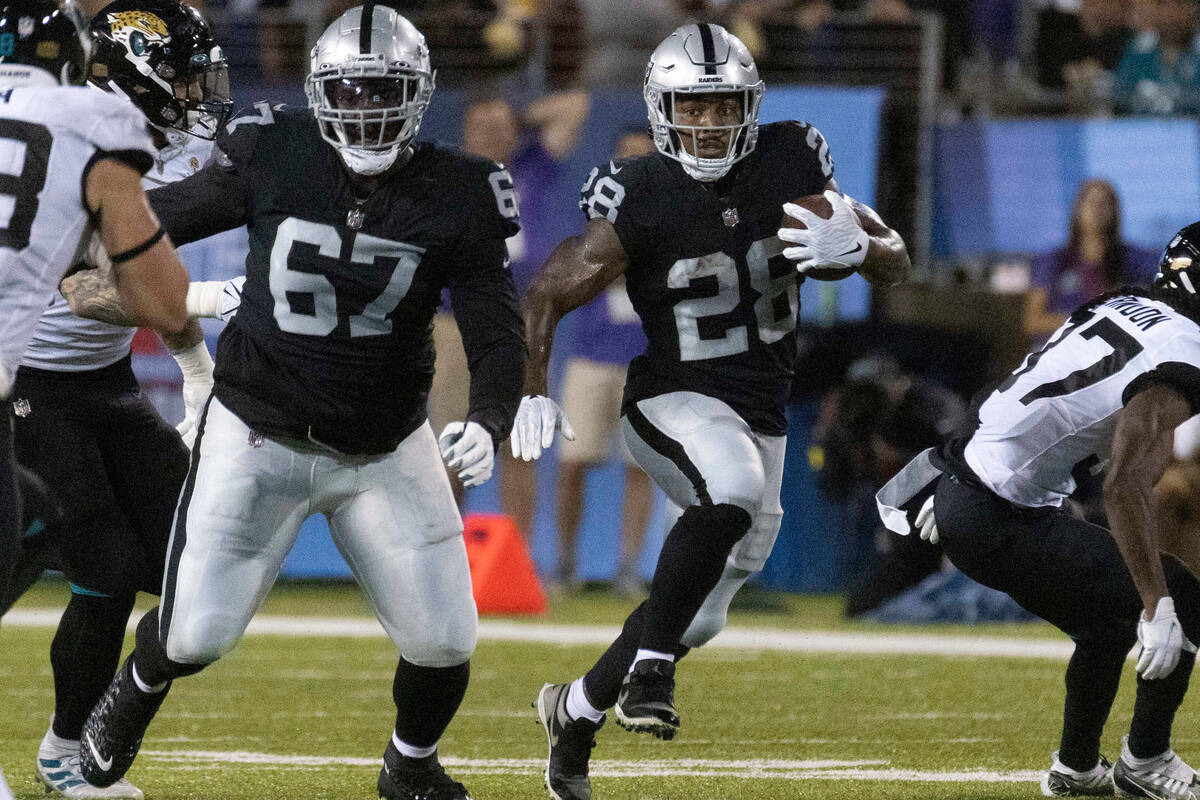 Raiders guard Lester Cotton Sr. (67) blocks as Raiders running back Josh Jacobs (28) finds more ...