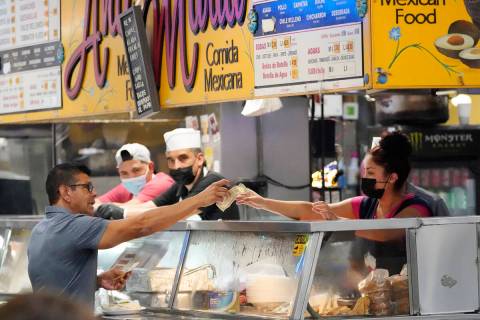 Money is exchanged at a food stand while workers wear face masks inside Grand Central Market on ...
