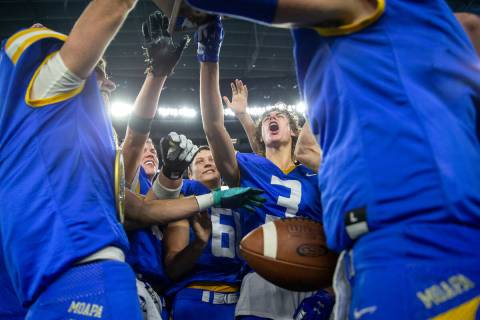 Moapa Valley players cheer while holding up their Class 3A football state championship trophy a ...