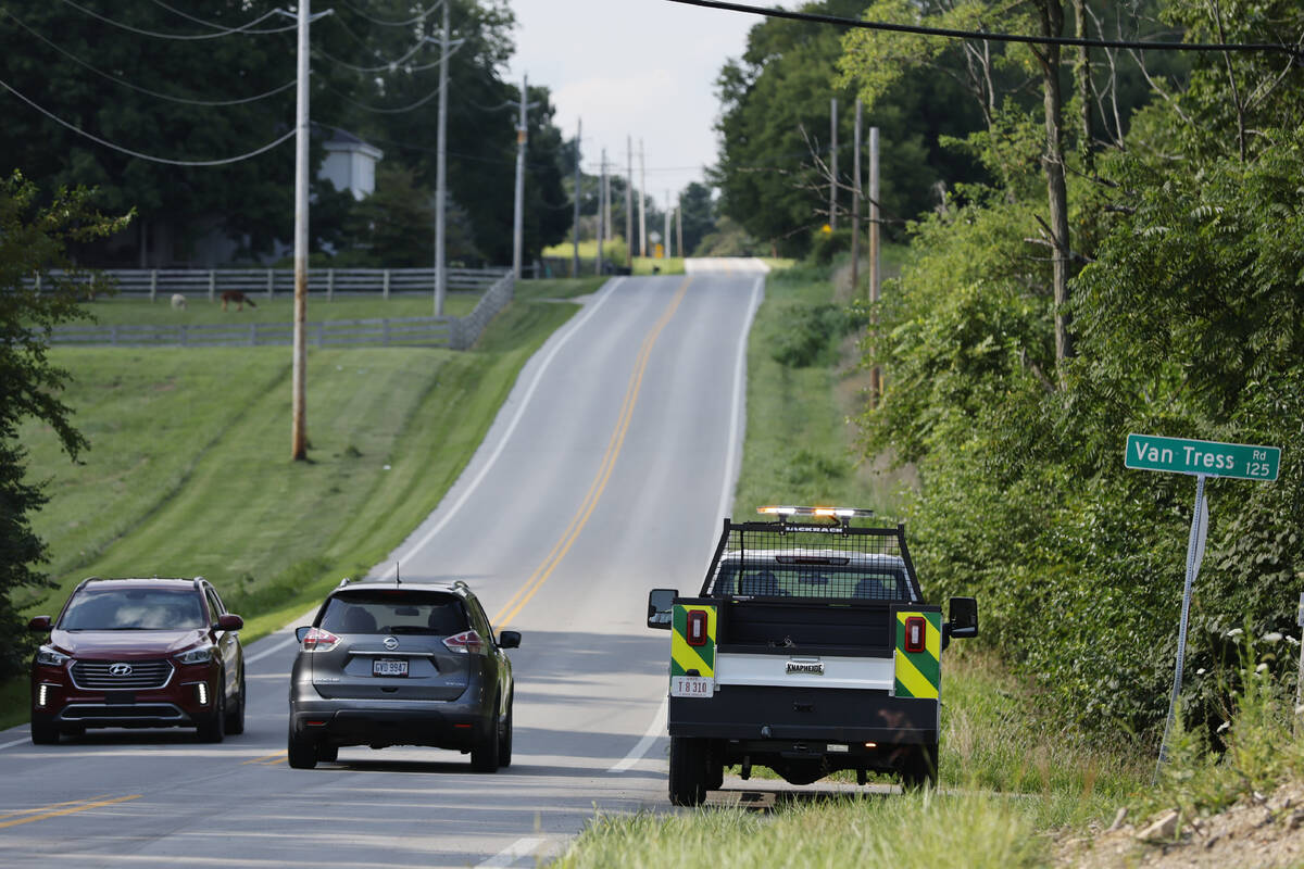 Clinton County employees sit in their vehicles blocking the road that leads to the scene where ...