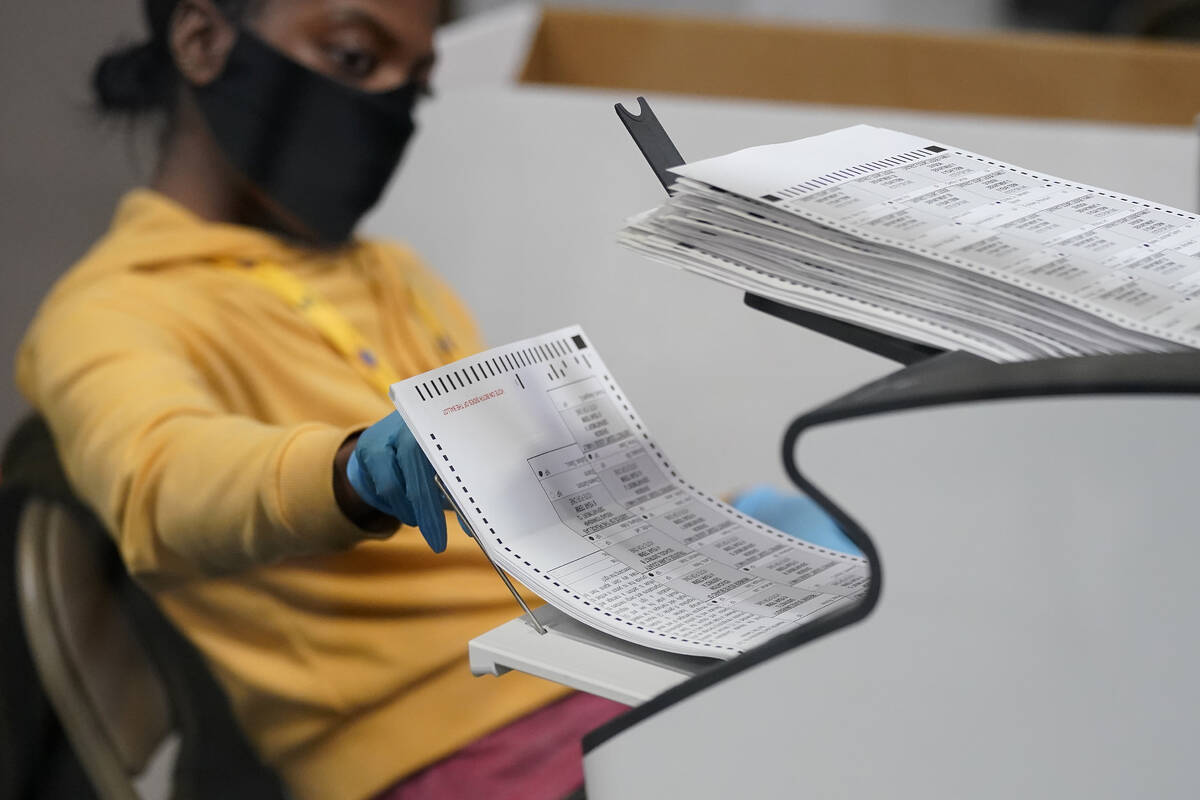 A county election worker scans mail-in ballots at a tabulating area at the Clark County Electio ...