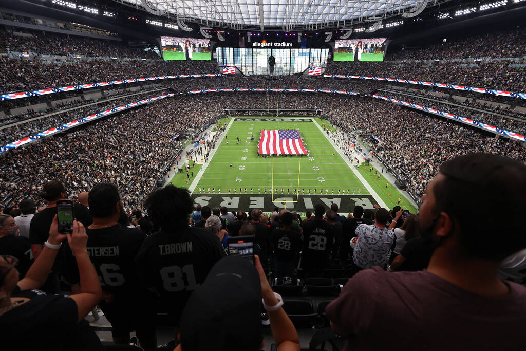 Fans listen to the singing of the national anthem before the start of a NFL preseason game betw ...