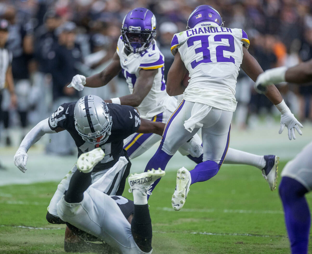 Vikings running back Ty Chandler (32) leaps away from a tackle attempt as Raiders cornerback Ch ...