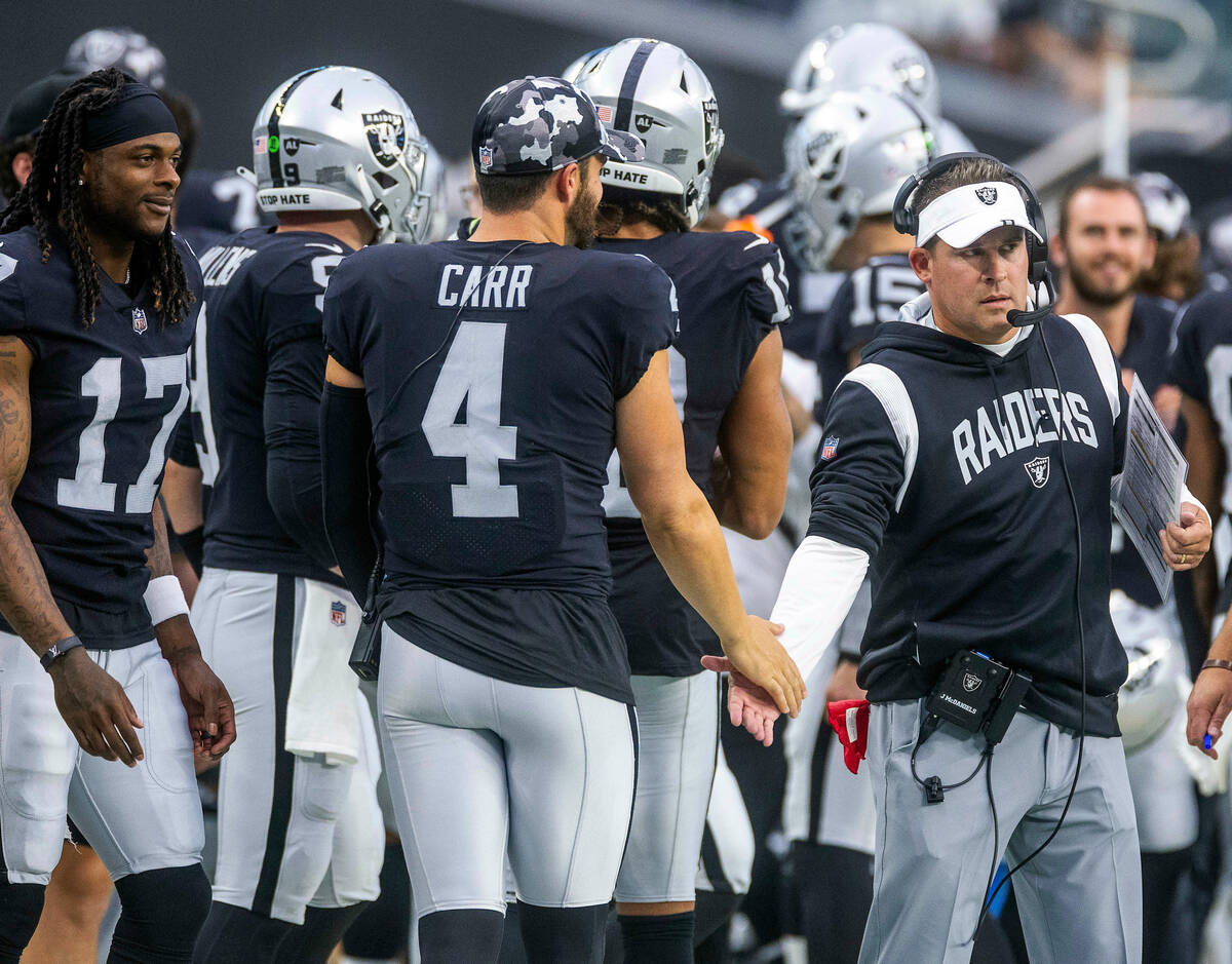 Raiders quarterback Derek Carr (4) slaps hands with head coach Josh McDaniels after a score dur ...