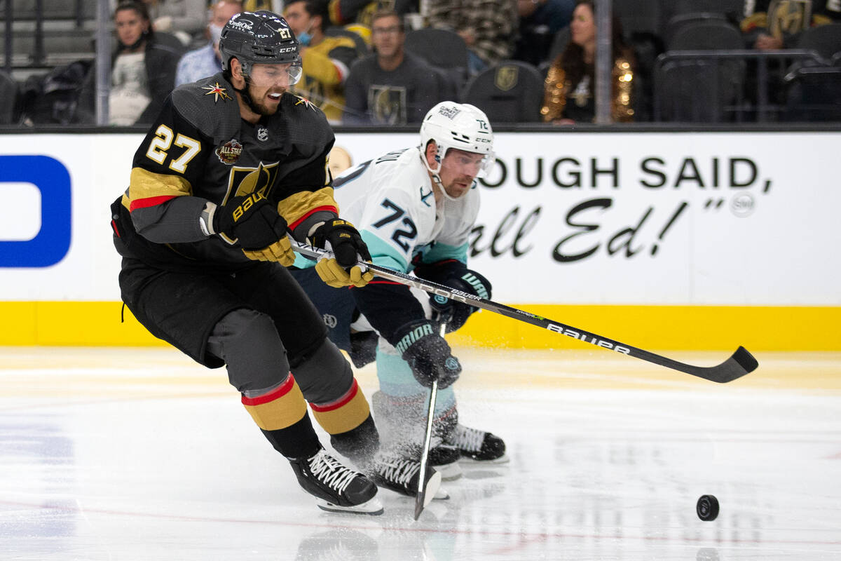 Golden Knights defenseman Shea Theodore (27) and Kraken right wing Joonas Donskoi (72) compete ...