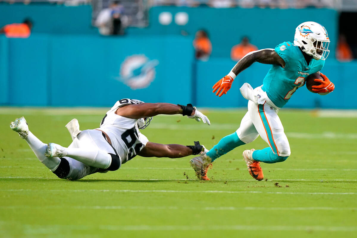 Miami Dolphins running back Chase Edmonds (2) avoids a tackle by Las Vegas Raiders defensive en ...