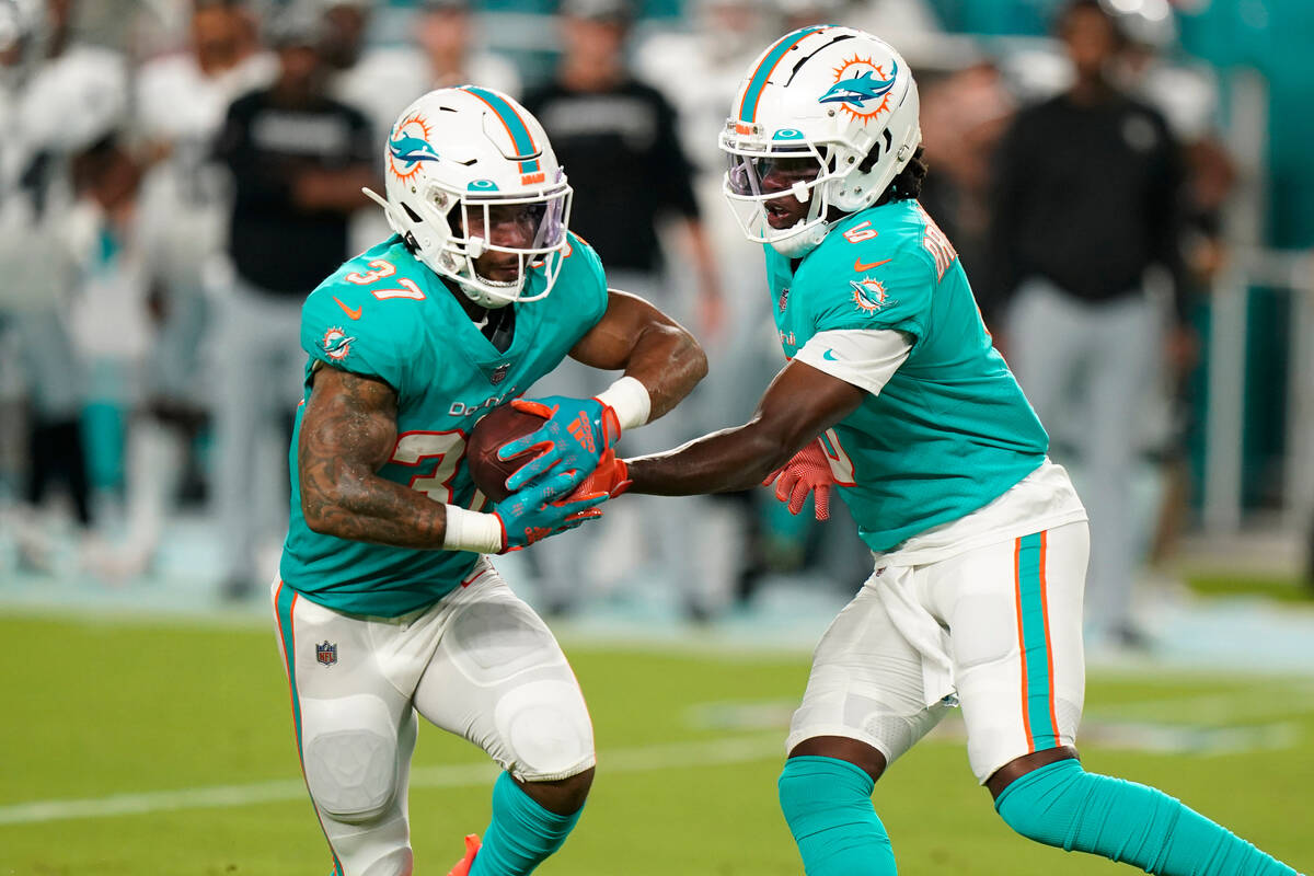 Miami Dolphins quarterback Teddy Bridgewater (5) hands the ball to running back Myles Gaskin (3 ...