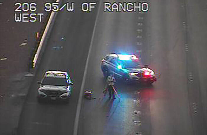 While shielded by a Nevada Highway Patrol cruiser, a photographer takes pictures on the southbo ...