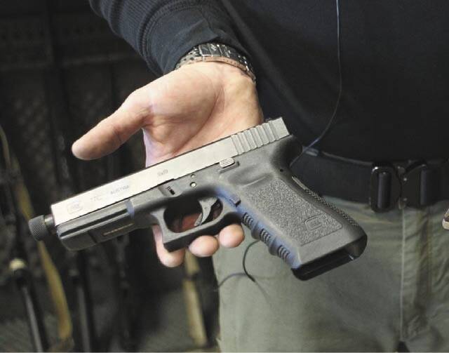 Matt Supnick holds a Glock semi-automatic pistol to explain the difference between a semi-autom ...