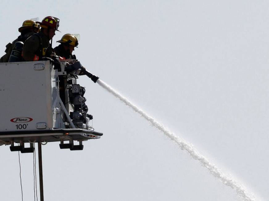 Firefighters try to extinguish a fire near Procyon Street, Tuesday, Aug. 23, 2022, in Las Vegas ...