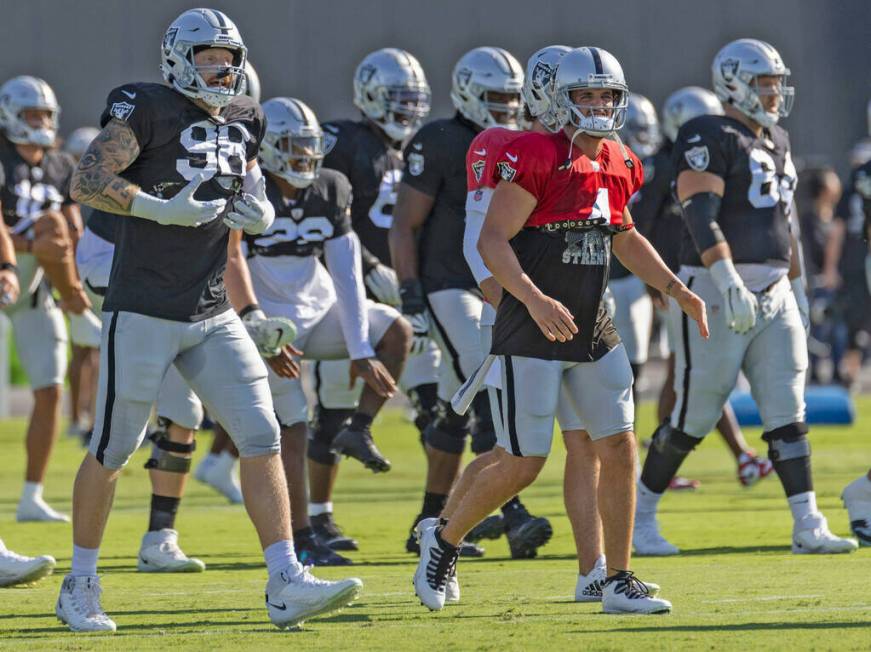 Raiders defensive end Maxx Crosby (98) and quarterback Derek Carr (4) stretch during the team&# ...