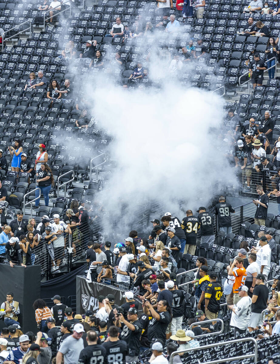 Raiders fans look on as smoke rises for players entering the field before the first half of the ...