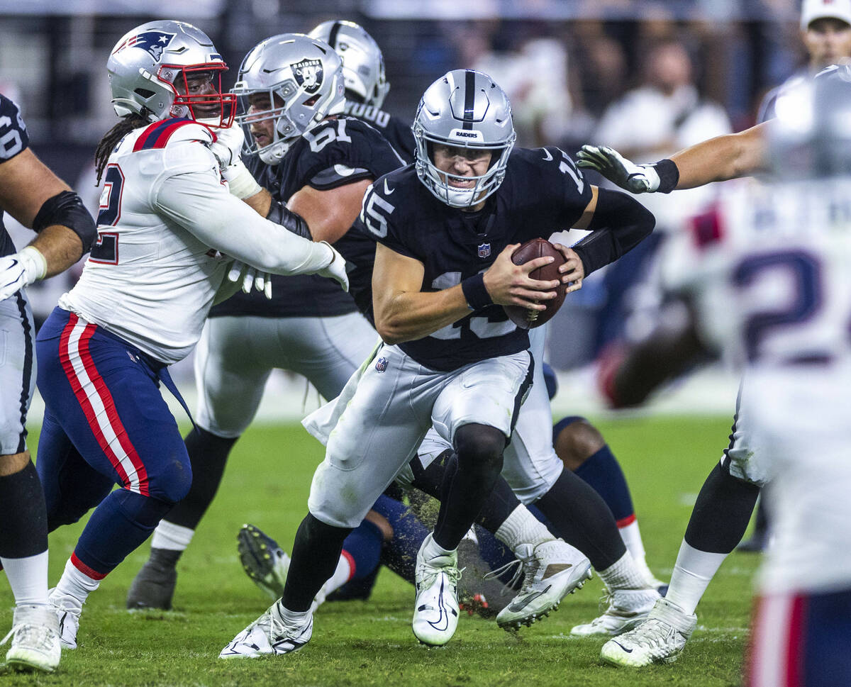 Raiders quarterback Chase Garbers (15) scrambles for yardage versus the New England Patriots du ...