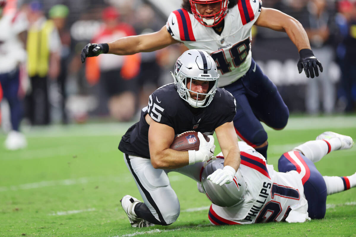 Raiders tight end Cole Fotheringham (85) is tackled by New England Patriots safety Adrian Phill ...