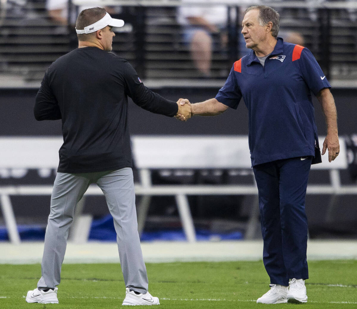 Raiders head coach Josh McDaniels, left, and New England Patriots head coach Bill Belichick sha ...