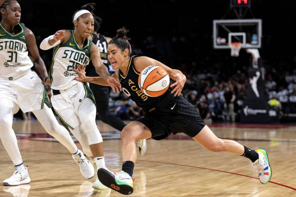 Las Vegas Aces guard Kelsey Plum (10) drives around Seattle Storm guard Briann January (20) and ...