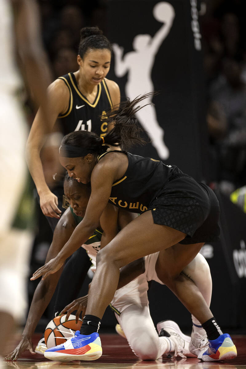 Las Vegas Aces guard Jackie Young (0) and Seattle Storm center Tina Charles, center left, compe ...