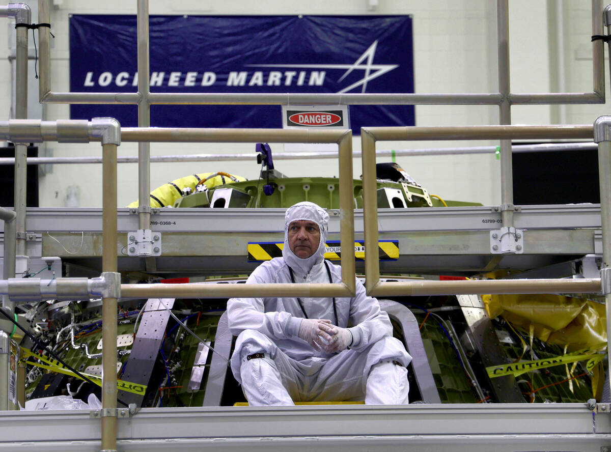 An Orion program engineer sits near the Artemis II crew capsule being assembled at Kennedy Spac ...