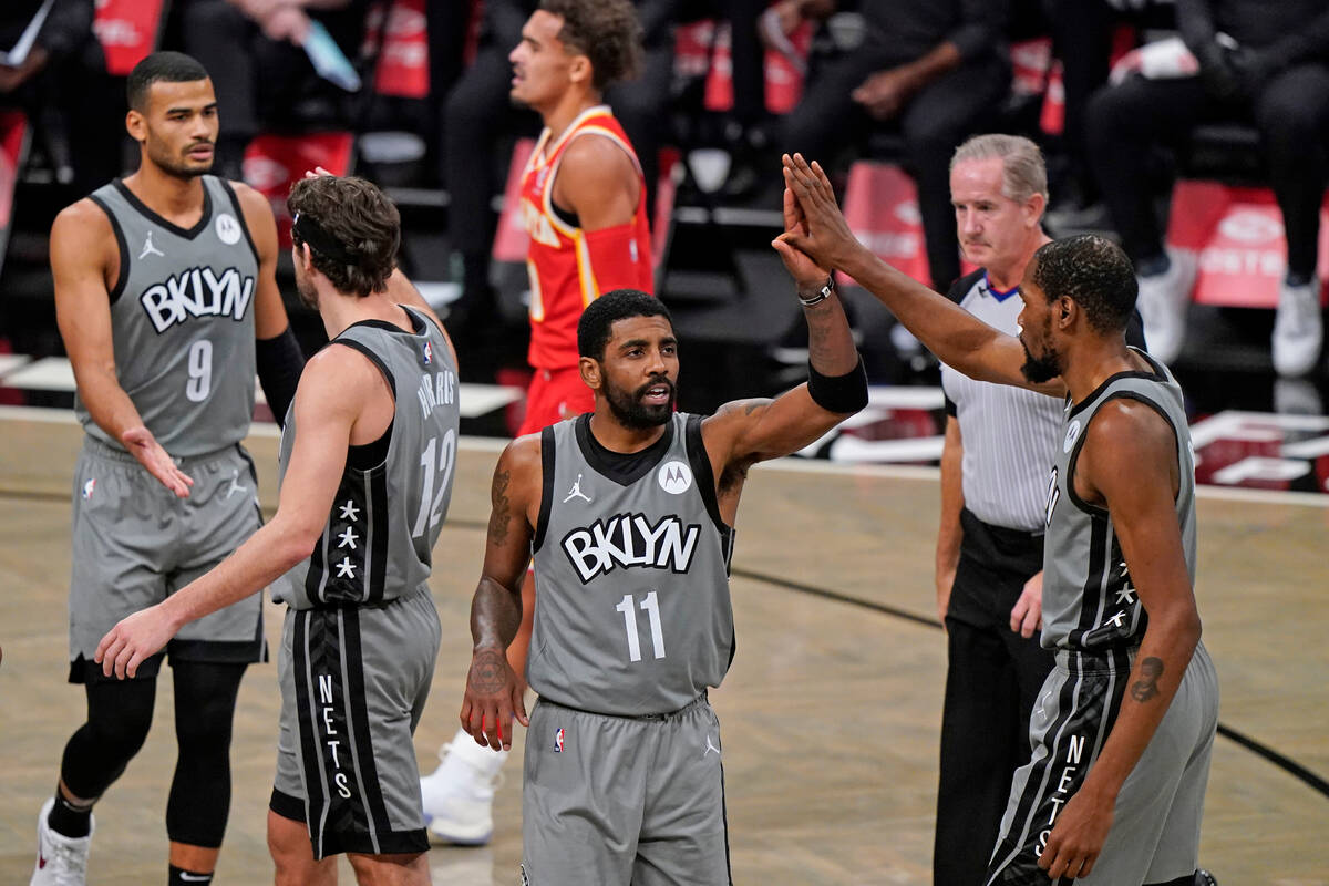 Brooklyn Nets guard Kyrie Irving (11) slaps hands with forward Kevin Durant, far right, as Nets ...