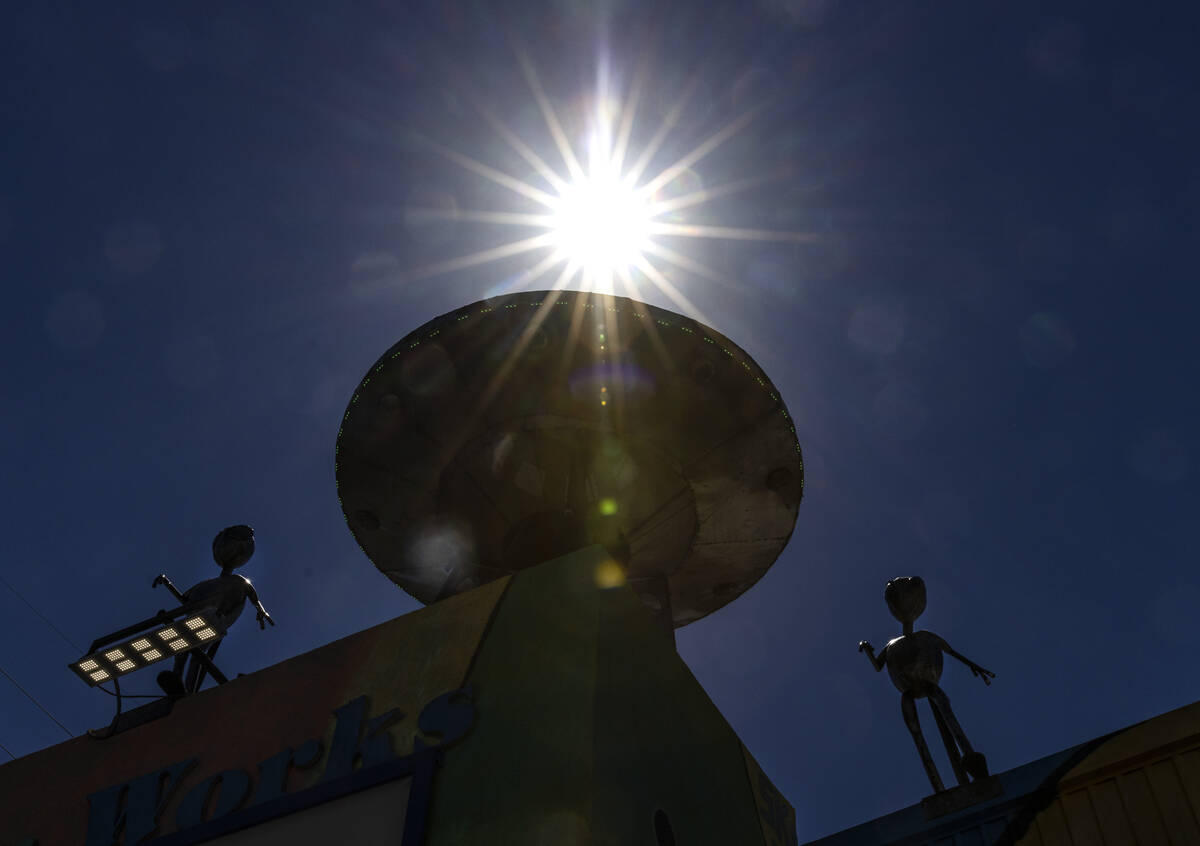 The afternoon sun light rays pierce through a metal Aliens sculpture and their craft outside of ...