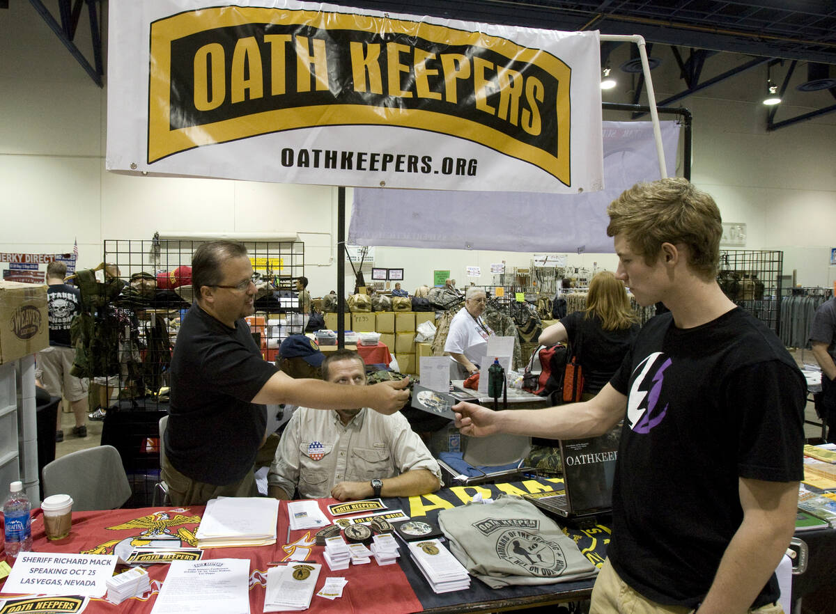 Stewart Rhodes, founder and spokesman of the Oath Keepers, left, gives a DVD to Kyle Zortman, 1 ...