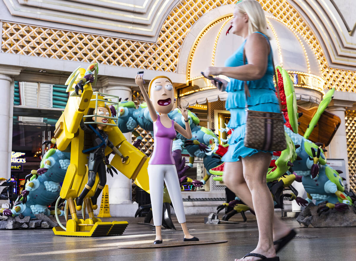 A pedestrian walks past figures of characters from the Adult Swim TV show "Rick and Morty," Spa ...