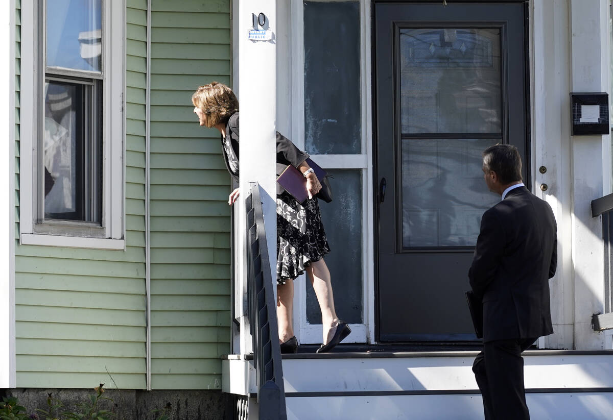 Carrie Sideris, of Newton, Mass., talks to a resident through a window accompanied by her husba ...