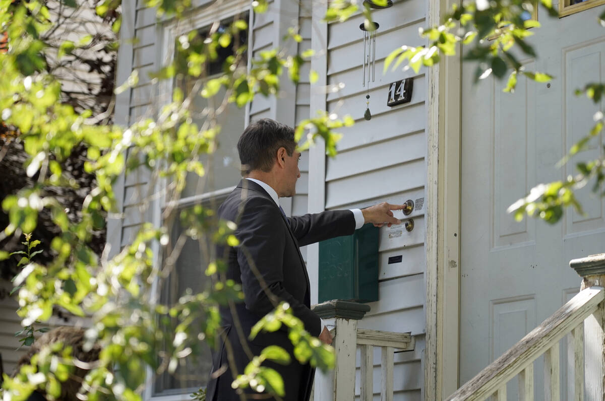 Dan Sideris, of Newton, Mass., rings a doorbell of a home as he and his wife return to door-to- ...