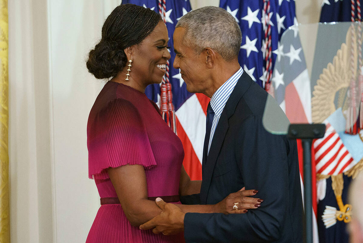 Former US president Barack Obama and wife Michelle Obama embrace during the unveiling of the Ob ...