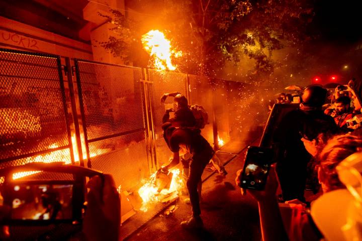 FILE - Protesters throw flaming debris over a fence at the Mark O. Hatfield United States Court ...