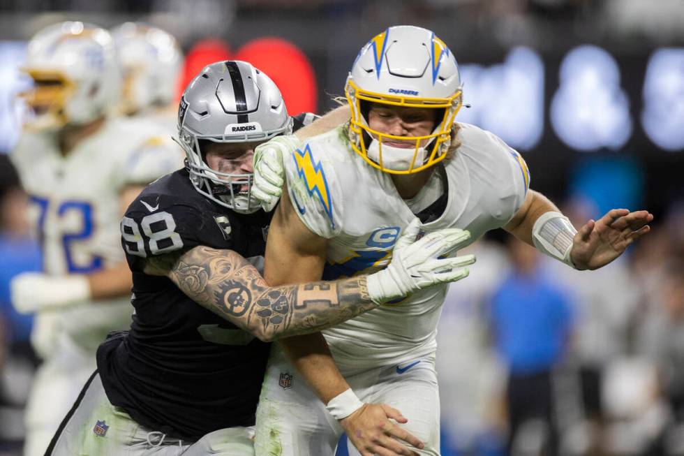 Raiders defensive end Maxx Crosby (98) hits Los Angeles Chargers quarterback Justin Herbert (10 ...