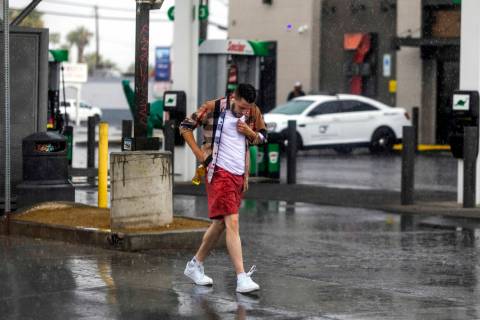 A pedestrian begins to get wet while walking in the rain along South Rainbow Boulevard on Satur ...