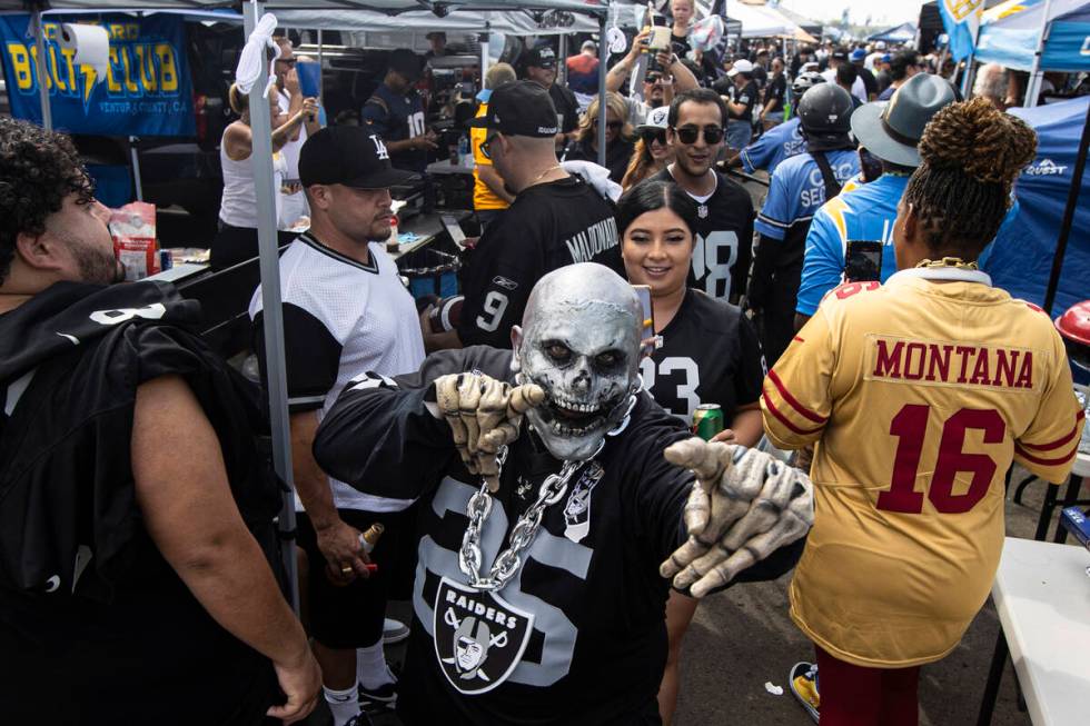 Raiders fans walk around a tailgate area before the start of an NFL game at SoFi Stadium on Sun ...