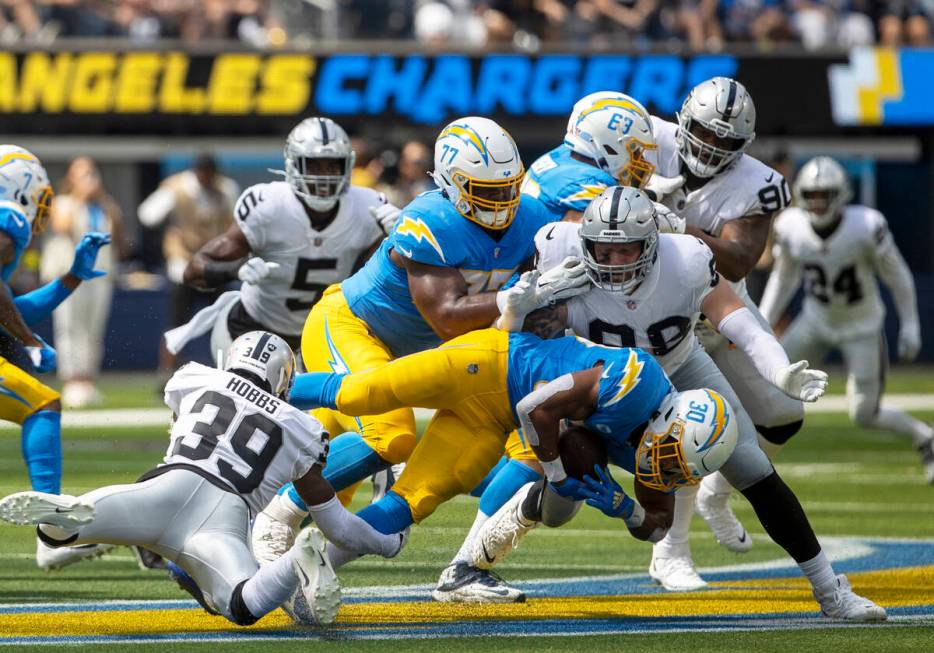 Raiders cornerback Nate Hobbs (39) and defensive end Maxx Crosby (98) tackle Los Angeles Charge ...