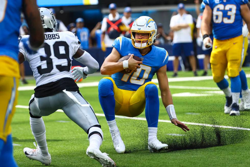 Los Angeles Chargers quarterback Justin Herbert (10) slides to the ground in front of Raiders c ...