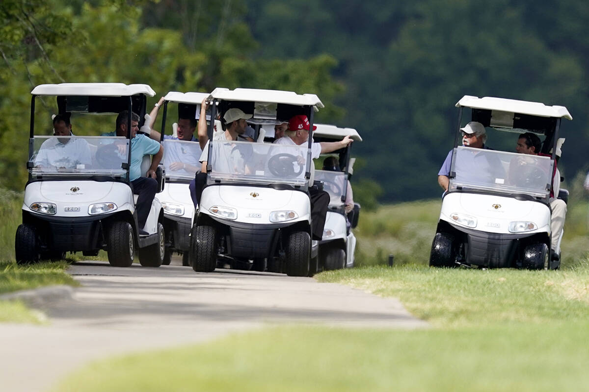 Former President Donald Trump, center cart, rides around his golf course at Trump National Golf ...