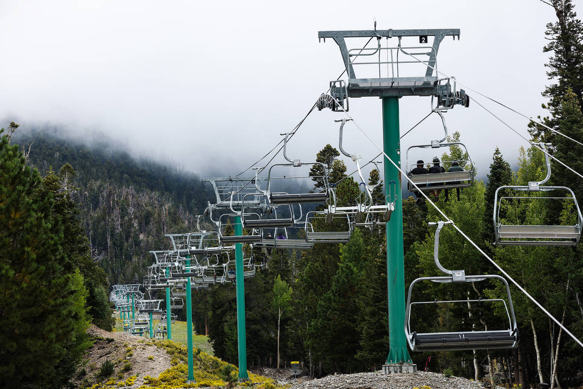 Bicyclists take the ski lift up to ride down paths as part of the downhill mountain bike park a ...