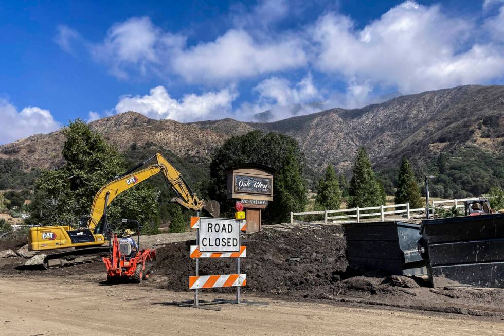 Heavy machinery clears the aftermath of a slow-moving black river of sludge in Oak Glen, Calif. ...