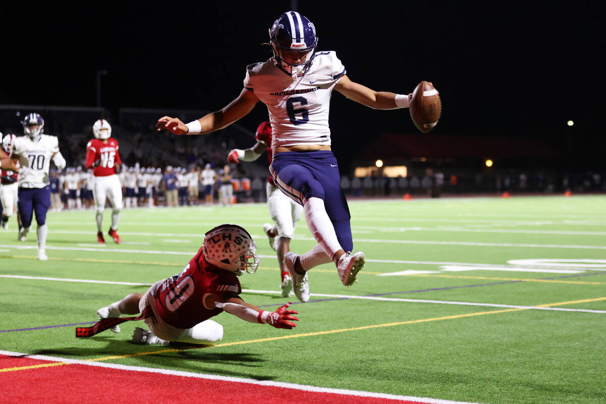 Kamehameha Kapalama's quarterback (6) leaps into the end zone for a touchdown while avoiding a ...