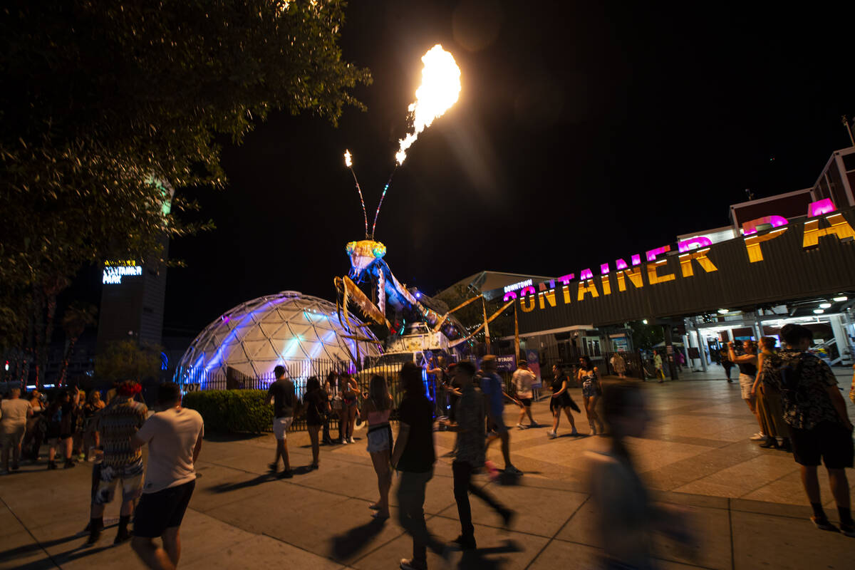 Attendees walk by the pyrotechnic praying mantis at the Container Park during the first day of ...