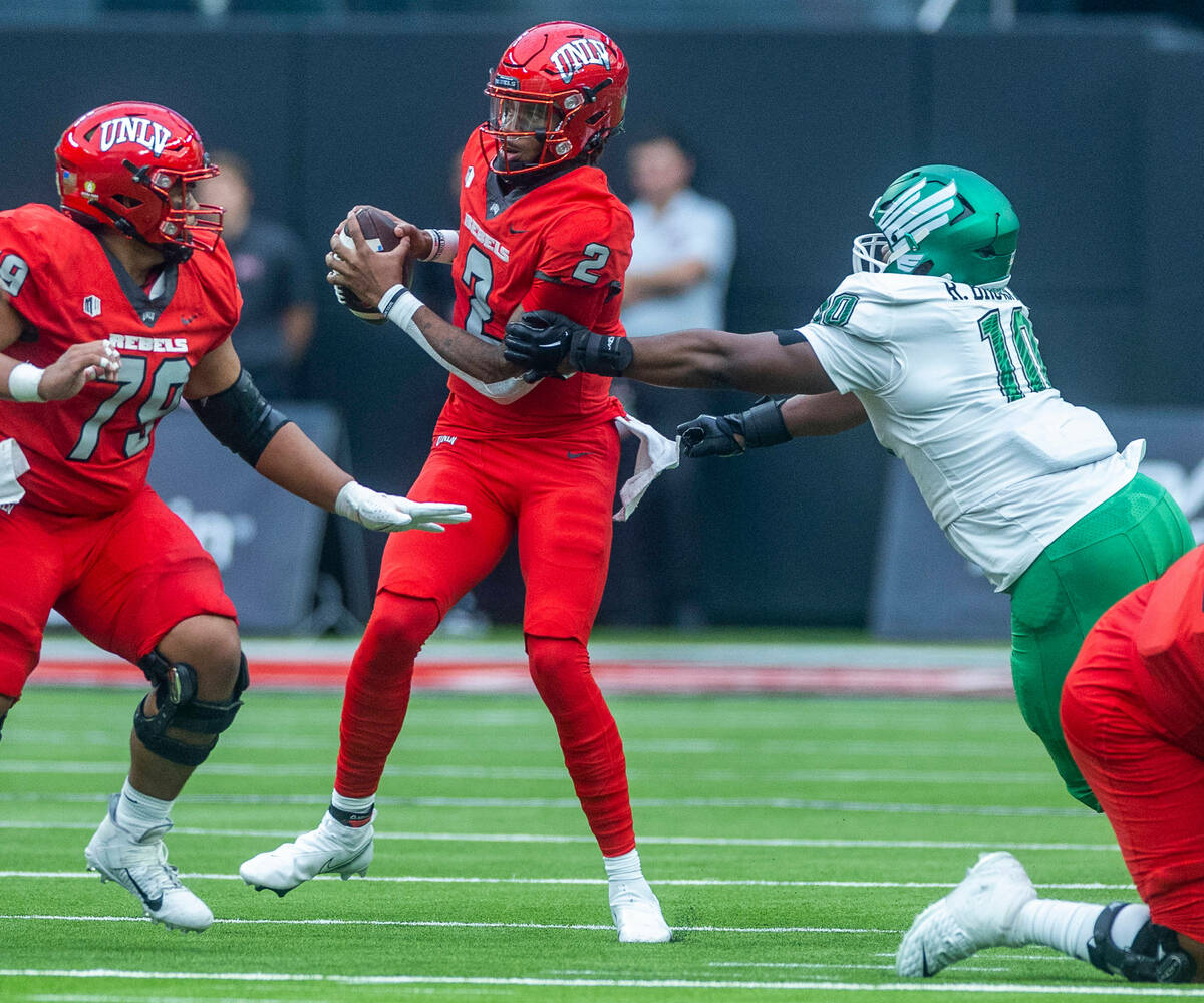 UNLV Rebels quarterback Doug Brumfield (2) attempts to avoid a sack by North Texas Mean Green d ...