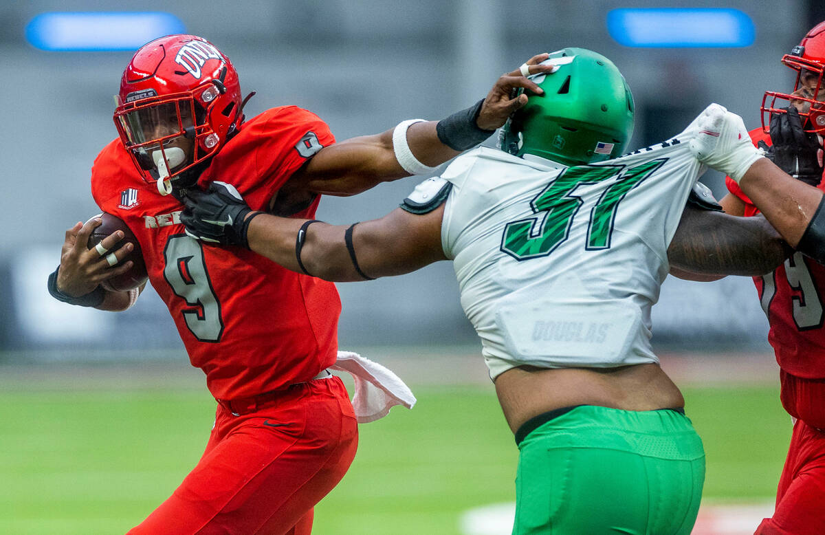 UNLV Rebels running back Aidan Robbins (9) pushes off a tackle attempt by North Texas Mean Gree ...