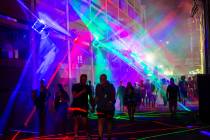 Attendees walk through an alleyway with projected lights during the Life is Beautiful festival ...