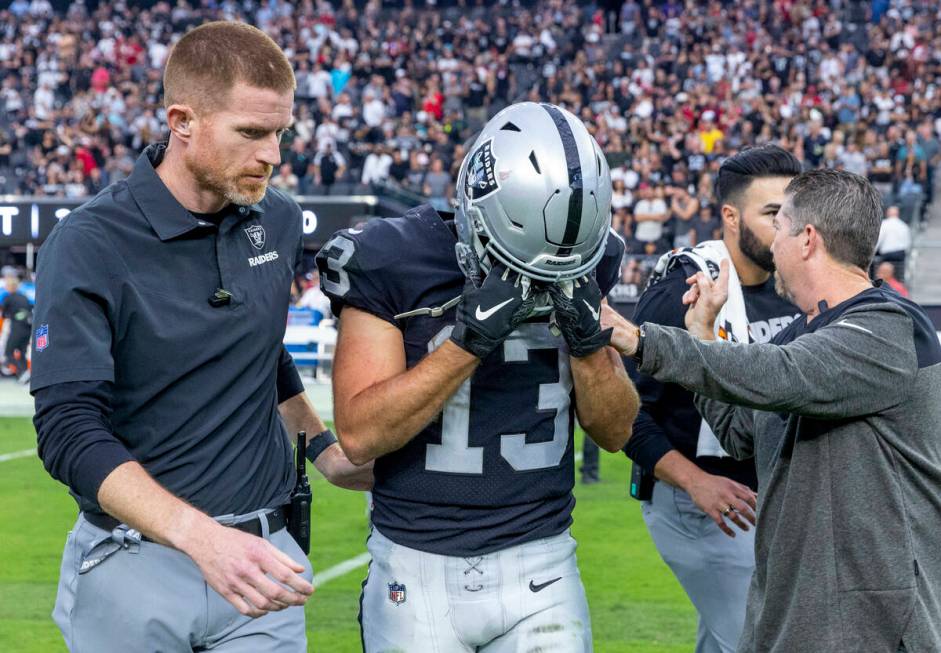 Raiders wide receiver Hunter Renfrow (13) is helped off the field after a big hit forced a fumb ...