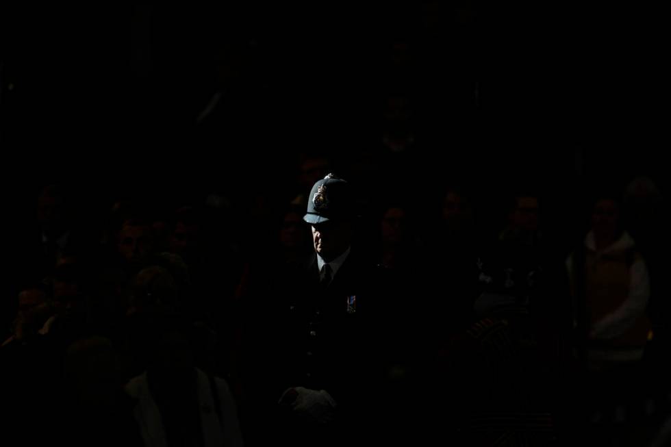 A ray of sun shines on a police officer as he stands guard near the coffin of Queen Elizabeth I ...