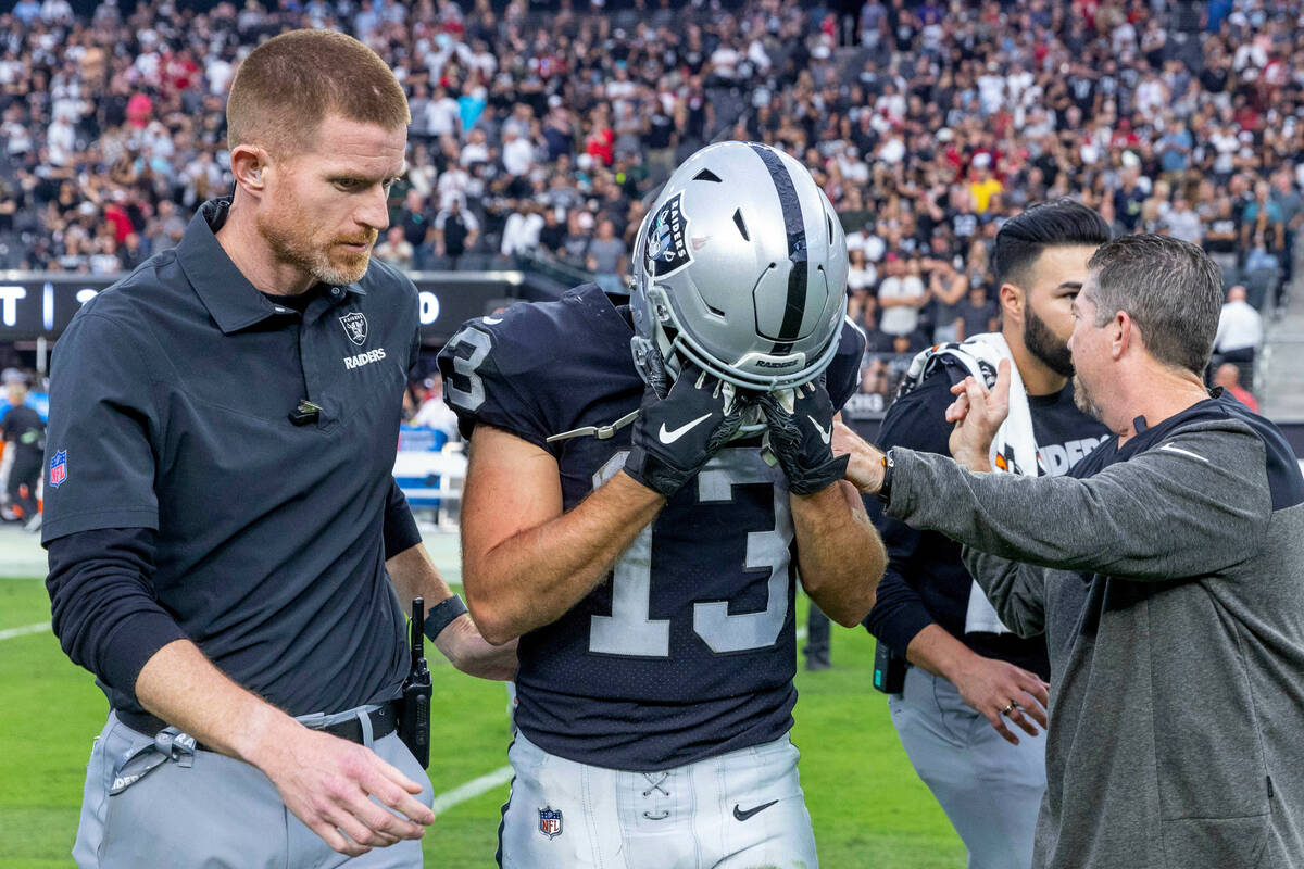 Raiders wide receiver Hunter Renfrow (13) is helped off the field after a big hit forced a fumb ...